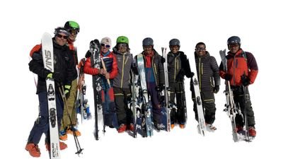 Group of skiers with helmets and skis standing on a snow-covered mountain.