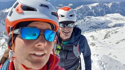 Two people with helmets and sunglasses mountaineering in the snowy high mountains.