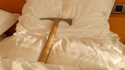 An ice pick lies on a white pillow in a bed.