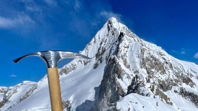 Ice pick in front of a snow-covered mountain peak under a blue sky.