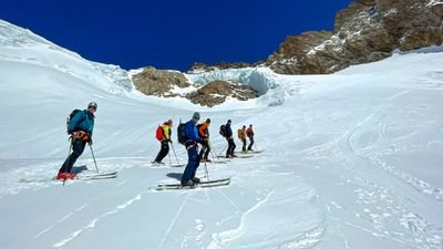 People with skis and helmets are skiing in the snow in the mountains.