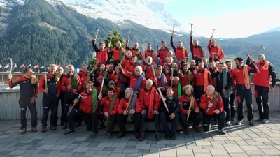 Group of people in red jackets with ice axes in front of a mountain backdrop.