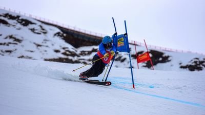 Skier with helmet and ski poles slaloms on a snow-covered mountain.