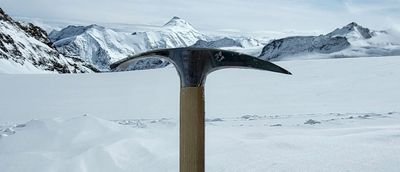 Ice axe in the snow in front of a snowy mountain landscape in Switzerland.