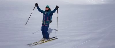 Person on skis with poles and helmet in a snow-covered mountain landscape.