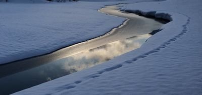 Snow-covered landscape with a narrow river winding through the terrain.