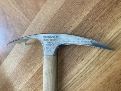 Ice pick with engraving lying on wooden surface.