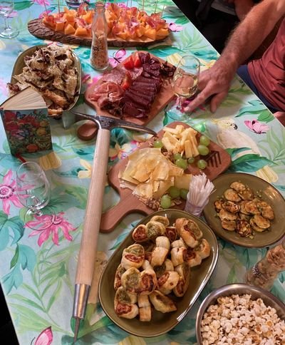 A table with various foods, including meat, cheese, pastries, and an ice pick.