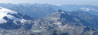 Mountain landscape in Switzerland with snow-covered peaks and a turquoise lake in the valley.