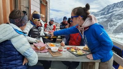 Woman serves a group at the Konkordiahütte for an aperitif