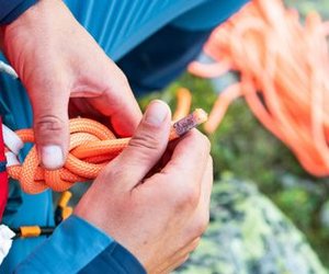Bergsteiger macht einen Achterknoten ins Seil