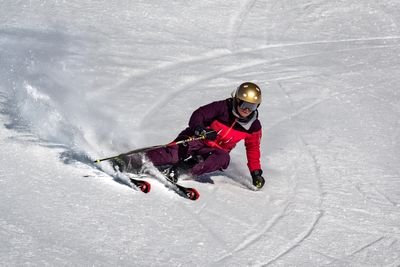 Person on skis with a helmet is skiing down a snowy slope.