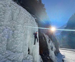 Person ice climbing with the sun in the background