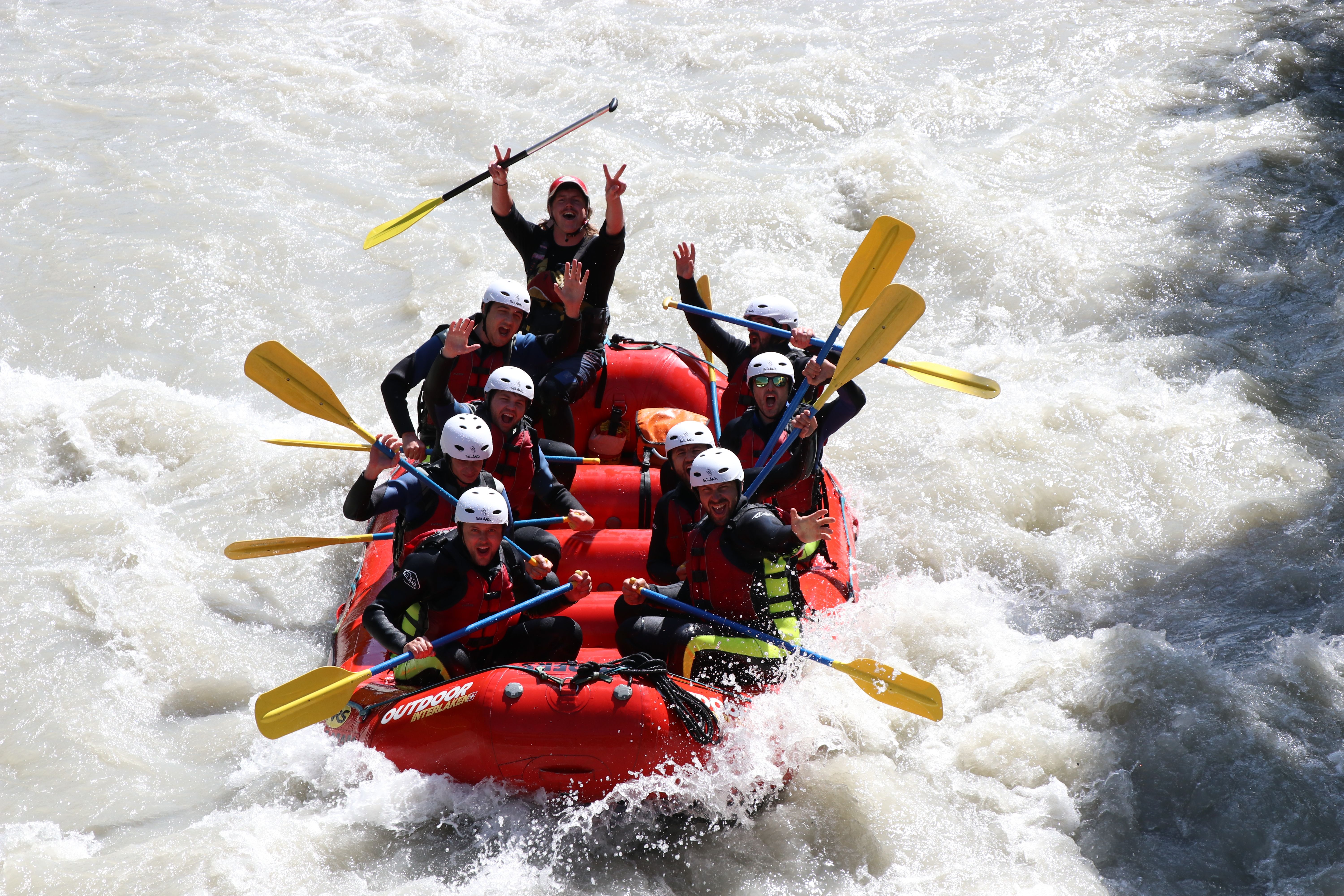People in an inflatable boat with helmets and paddles on a wild river.