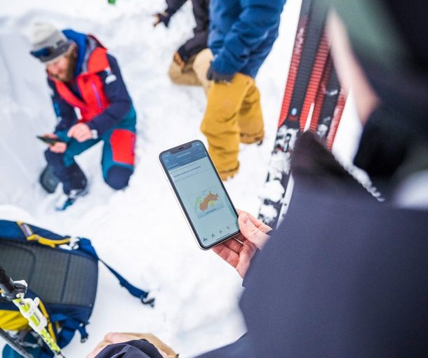 Teilnehmende Lawinenkurs informieren sich am Handy über die Lawinensituation