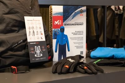 Outdoor-Bekleidung und -Ausrüstung, darunter Handschuhe und ein blauer Anzug, auf einem Tisch ausgestellt.