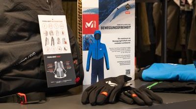 Outdoor-Bekleidung und -Ausrüstung, darunter Handschuhe und ein blauer Anzug, auf einem Tisch ausgestellt.