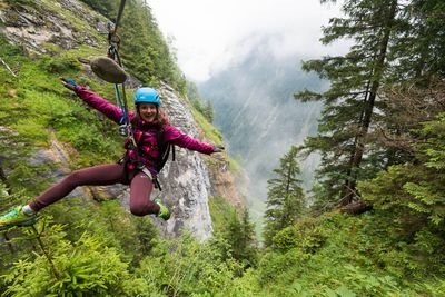 Frau auf Tyroliennebahn im Wald.