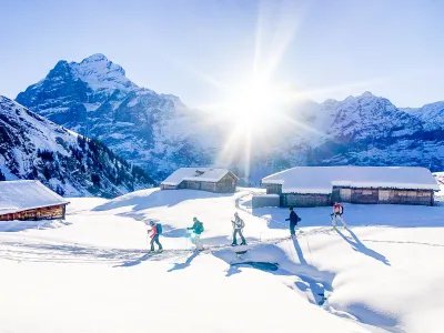 Skitourengänger im Aufstieg bei Alphütten mit dem Wetterhorn im Hintergrund