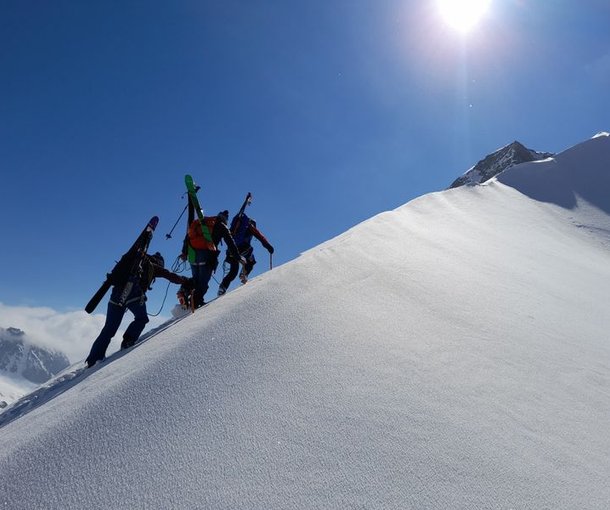Skitourengänger mit aufgebundenen Ski auf Grat