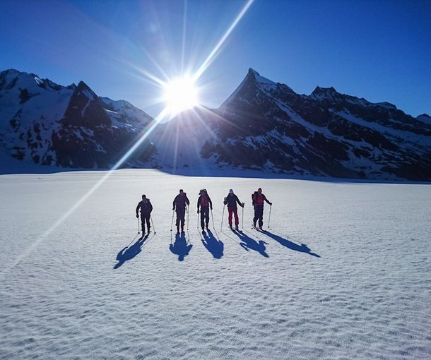 Skitourengänger auf dem Konkordiaplatz mit Sonnenaufgang im Hintergrund