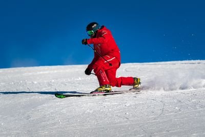 Person in red ski clothing and helmet skiing down a snow-covered slope.