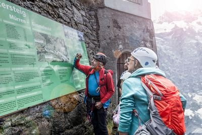 Bergführer erklärt Route des Klettersteig Mürrens auf Karte. Gäste schauen zu.