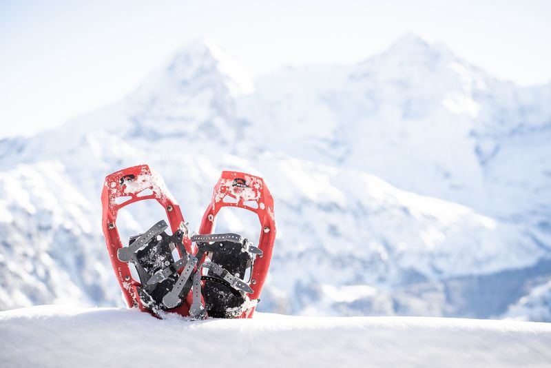 Red snowshoes in the snow in front of snow-covered mountains in Switzerland.
