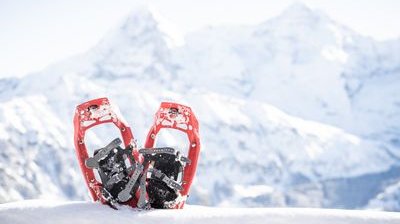 Red snowshoes in the snow in front of snow-covered mountains in Switzerland.