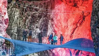 Personen auf einem gespannten Netz in einer beleuchteten Schlucht, umgeben von Felswänden.