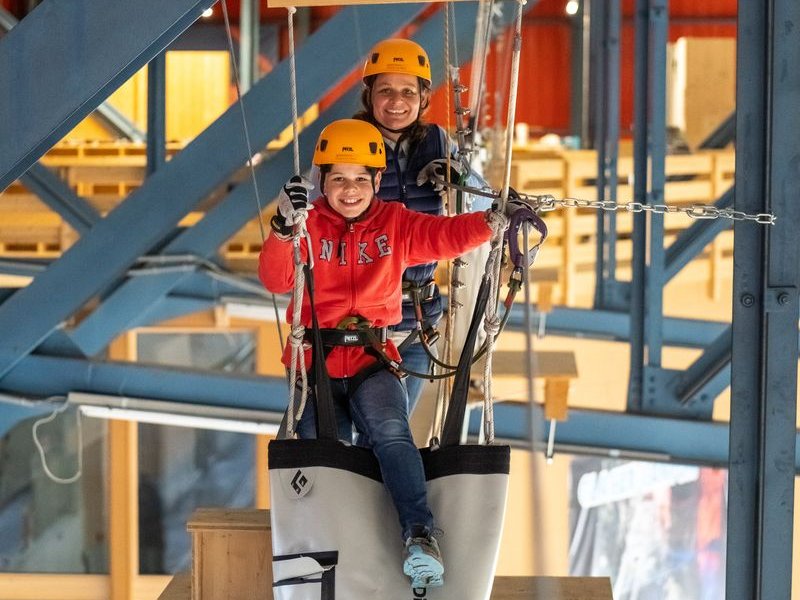 Two people happily overcome an obstacle at the Indoor Rope Park Grindelwald