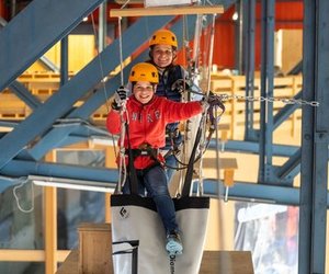 Zwei Personen überwinden lachend ein Hindernis im Indoor Seilpark Grindelwald