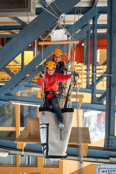 Two people happily overcome an obstacle at the Indoor Rope Park Grindelwald