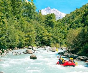 River-Rafting auf der Lütschine mit Helmen und Paddeln, umgeben von üppigem Wald und verschneite Berge im Hintergrund